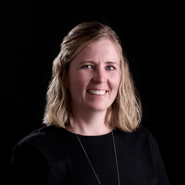 An image of Jenny Wright. She has blonde hair down to her shoulders, blue eyes, and a natural smile.